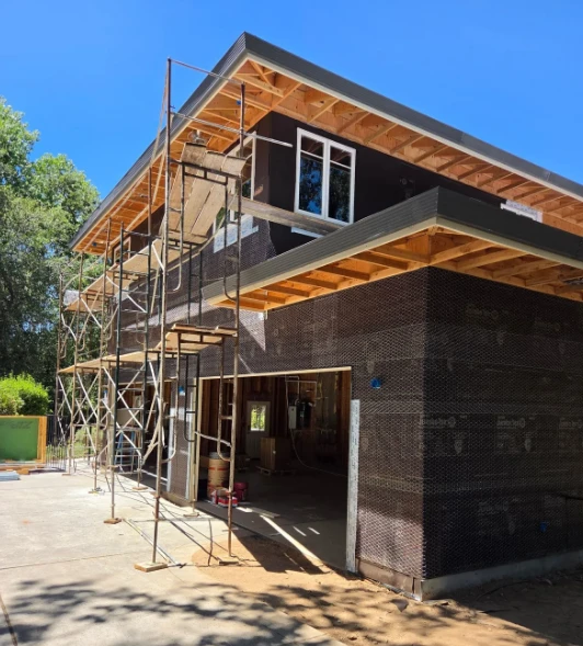 A two-story K Squared build, framed and wrapped, with scaffolding on the side
